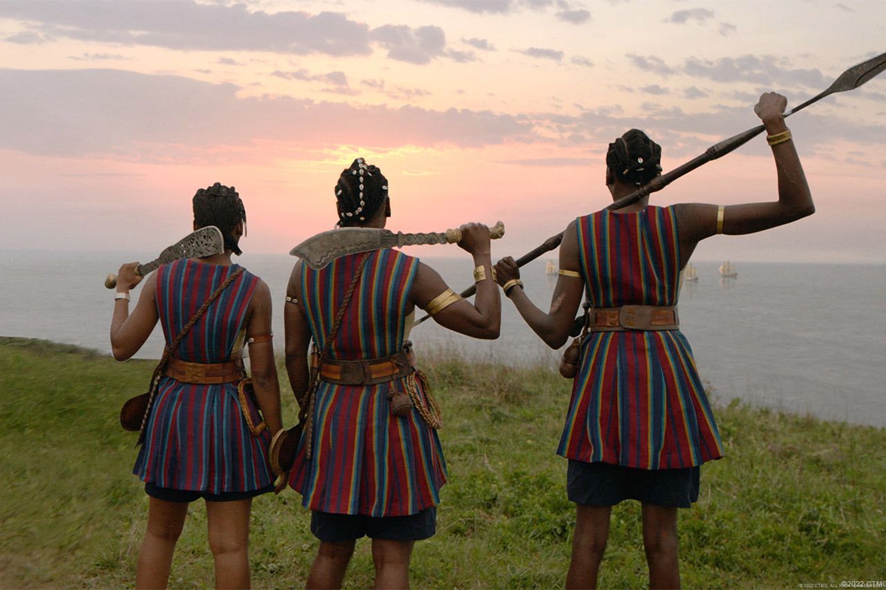 Three women warriors look out at the Atlantic Ocean and the sailing vessels of European slave traders