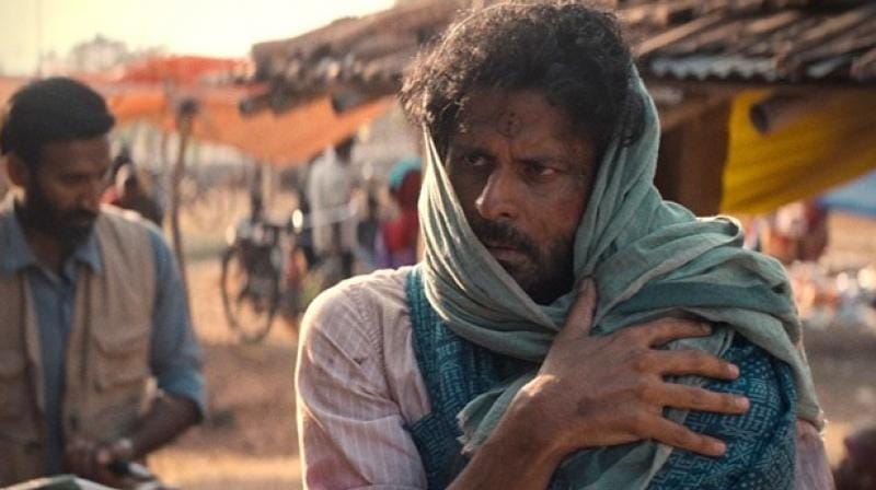A desperate father clings to his baby, swaddled and strapped to his chest, in a remote village in India.