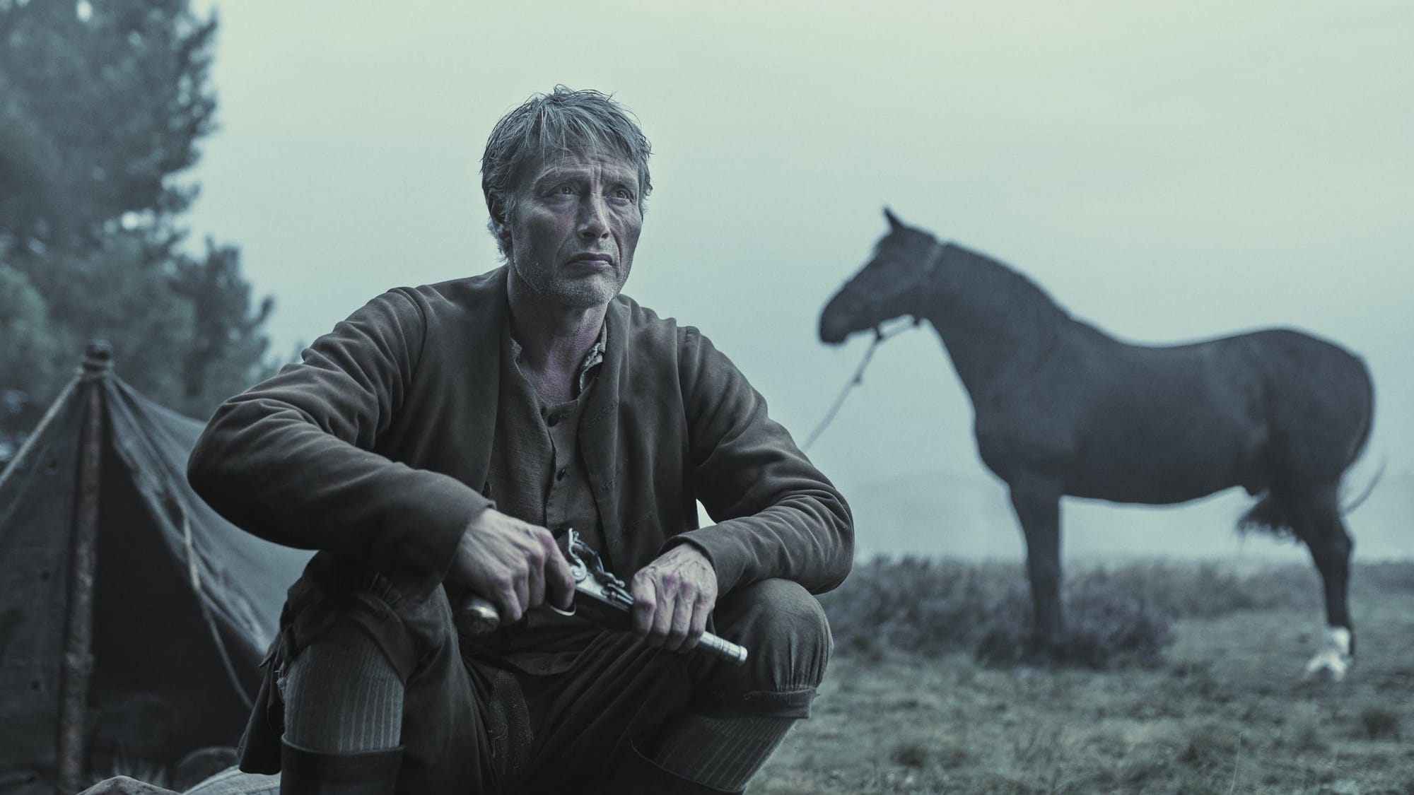 Mads Mikkelsen pensive, holding an antique pistol, in "The Promised Land"