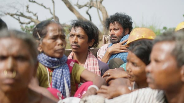 The fugitive father of the film Joram, riding in the back of a truck packed with passengers.